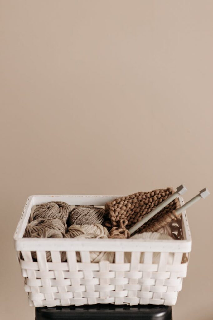 A white basket filled with yarn and knitting needles, perfect for crafting projects.