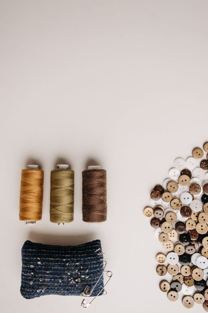 A creative flatlay of colorful sewing threads and assorted buttons on a light background.
